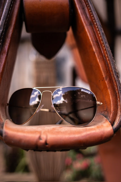 A pair of Branded Vision sunglasses resting in a stirrup.